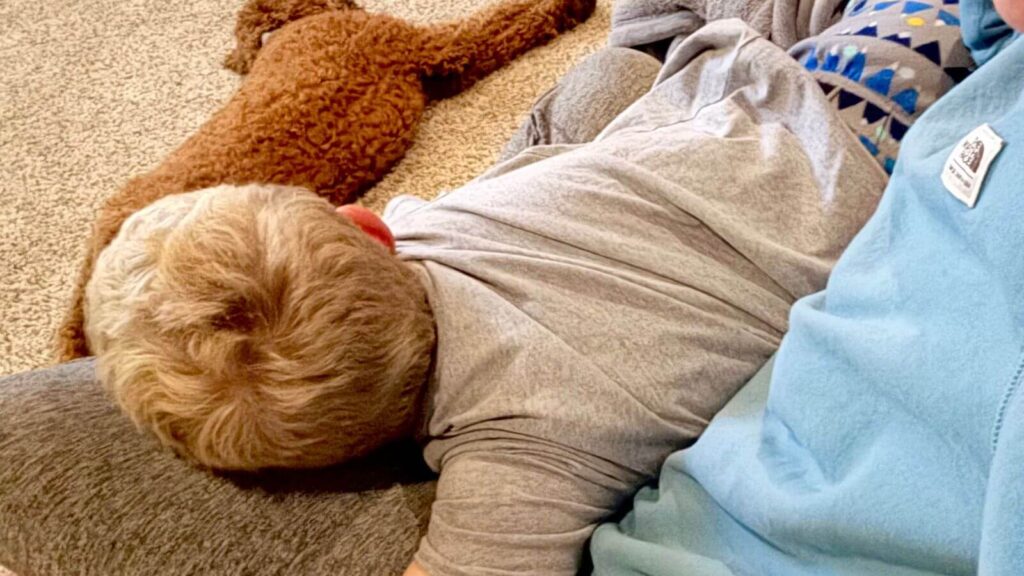 Mother and son resting together on the couch, a quiet reflection on boyhood and slowing time.